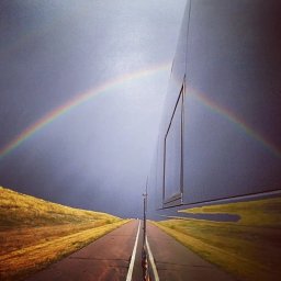 Tour bus with a rainbow reflection and storm in the background
